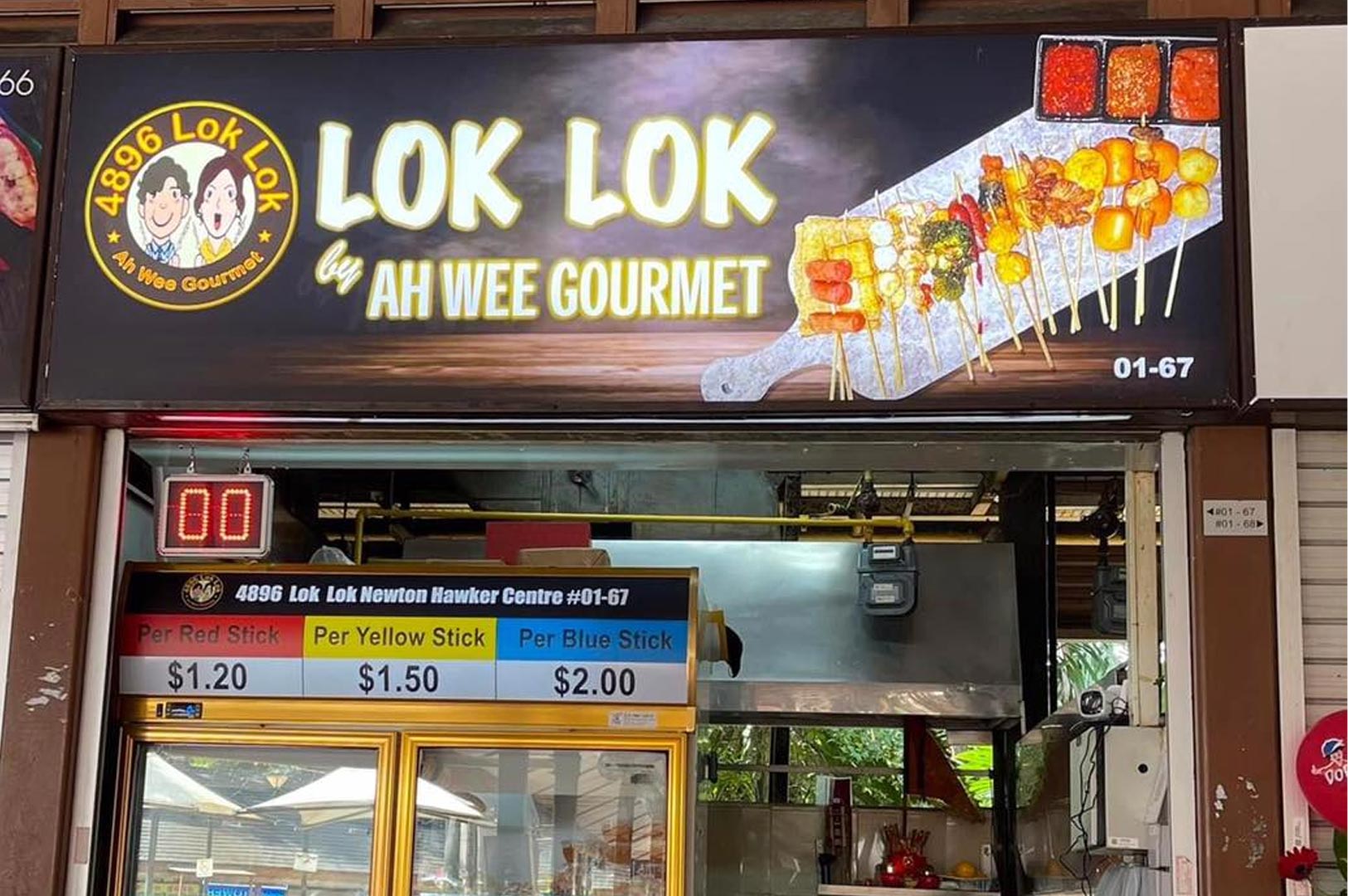 Signage for Lok Lok by Ah Wee Gourmet at Newton Food Centre, featuring a price list for color-coded food skewers.