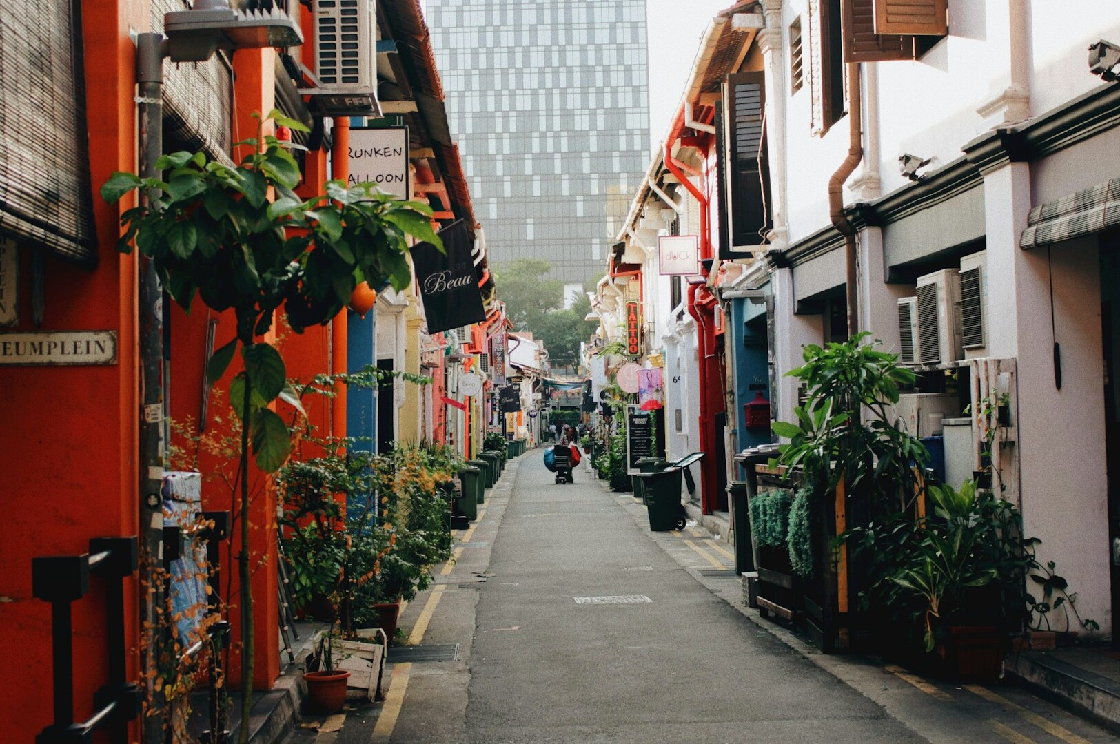 A narrow alleyway in Haji Lane, Singapore, with a colorful building visible in the background, showcasing hidden gems.