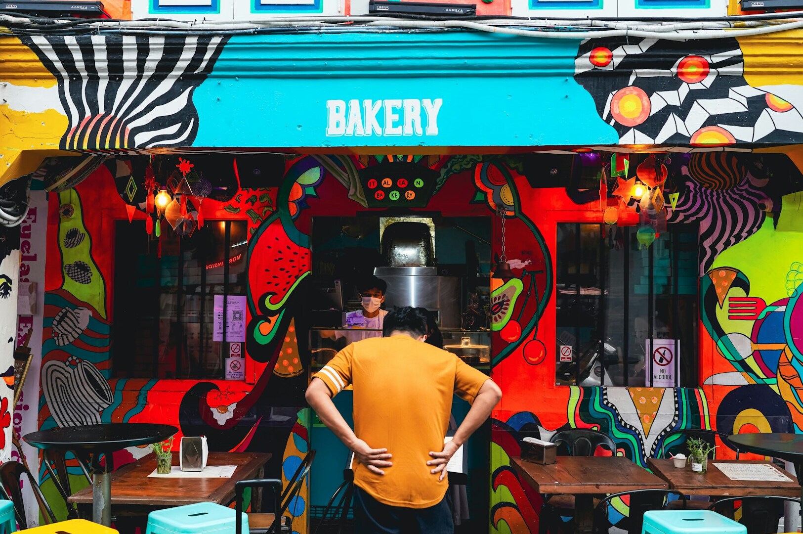 A man stands before a colorful cafe, emphasizing its unique appeal and inviting ambiance as a hidden gem.