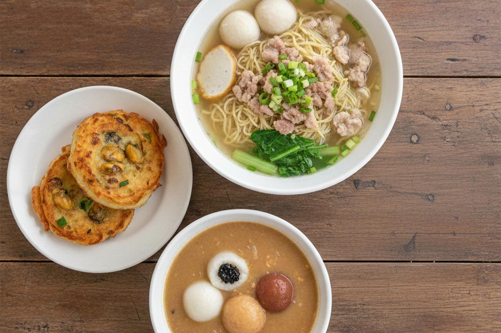 Top-down view of Singaporean hawker favorites: Bak Chor Mee soup, fried oyster cakes, and Ah Balling peanut soup.