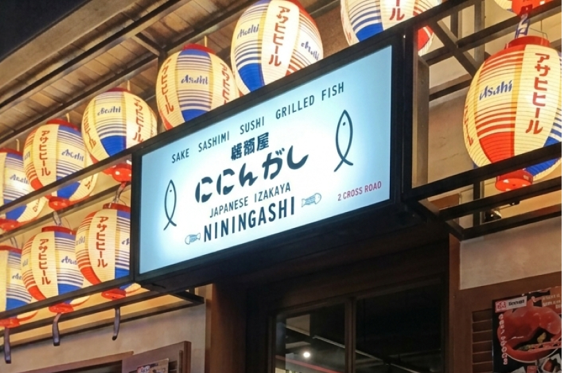 A glowing outdoor sign for "Niningashi Japanese Izakaya" surrounded by traditional white and red paper lanterns.