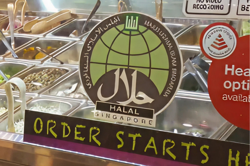 A close-up of a glass counter showing a Halal Singapore certification sticker and a sign that reads "Order Starts Here."