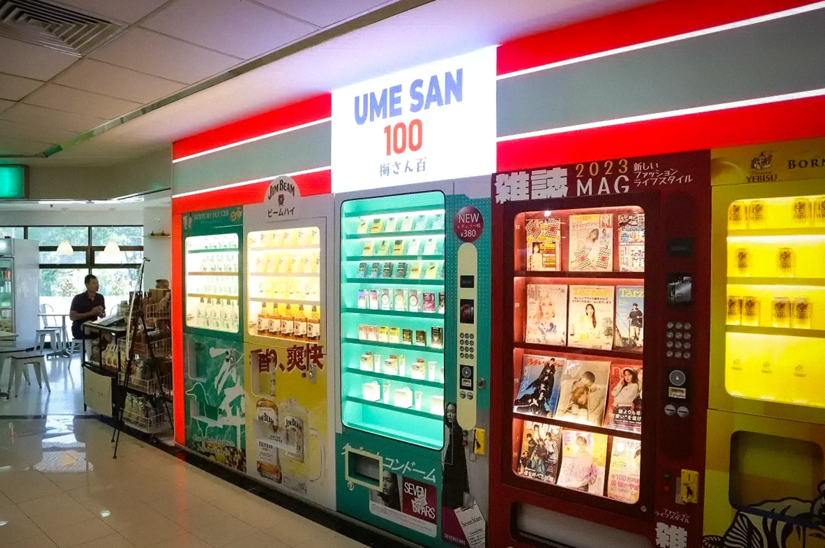 Colorful Japanese-themed vending machines and magazine dispensers inside UME SAN 100 in Singapore featuring drinks, snacks, and manga-style displays in a modern indoor space