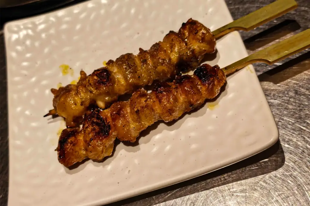Two skewers of freshly grilled Japanese yakitori chicken served on a white ceramic plate, showcasing tender, char-grilled chicken with a golden-brown glaze and smoky flavor.