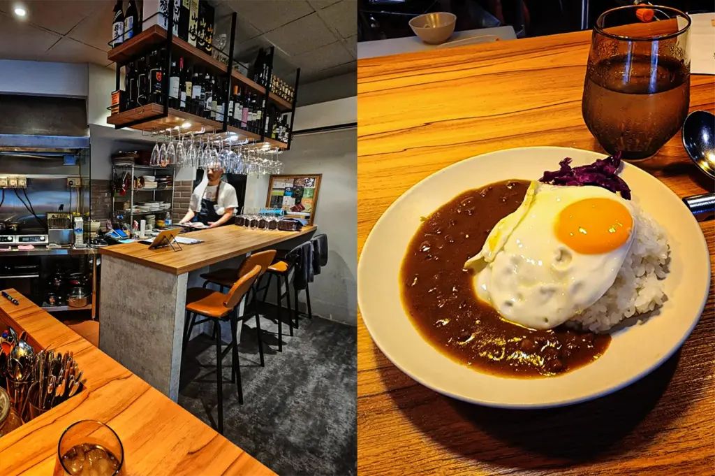 This split-composition image offers a detailed look at both the interior and a signature dish of a restaurant, representing the file "2-From Hidden Counters to Iconic Eateries 5 Best Japanese Curry.webp". On the left side, an eye-level shot captures a cozy, modern bar counter featuring an open kitchen setup where a chef in a white shirt and black apron stands behind a smooth wooden bar topped with leather stools. Above the counter, rows of wine glasses hang under multi-tiered shelves packed with wine and sake bottles. On the right side, a high-angle close-up showcases a plated meal served on a white dish atop a matching grained wooden table. The dish features a smooth, deep brown Japanese curry sauce paired with white rice, crowned with a sunny-side-up fried egg with a bright yellow yolk and accompanied by a small side of purple pickled cabbage, next to a sweating glass of water and metal utensils.